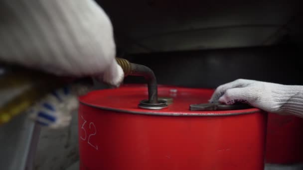 사람은 굴착기에 연료를 공급하기 위해 통 안에 펜치 튜브를 꽂아 고정 시킨다 — 비디오