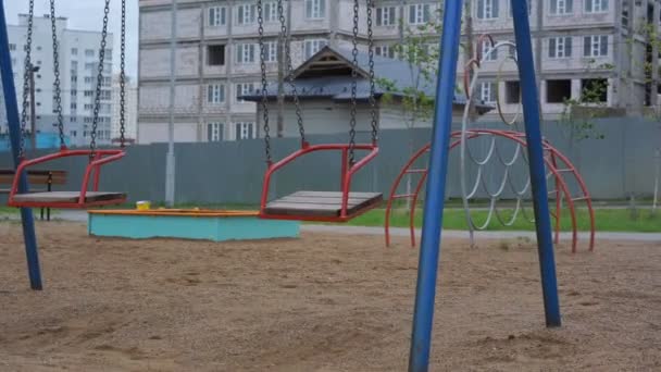 Un par de columpios rojos en cadenas se balancean en el parque infantil — Vídeos de Stock