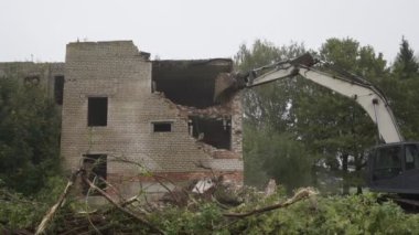 İşçi kazı kabininde oturuyor ve eski evleri yıkıyor.