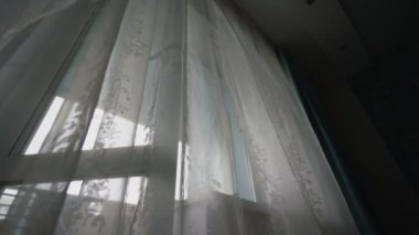 Yatak odasının camında plastik çerçeveli beyaz şeffaf perde asılı.