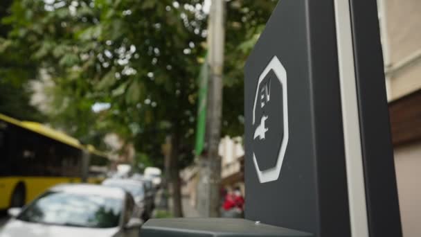 EV značka elektrického vozidla se zástrčkou obrázek na městském parkovišti.