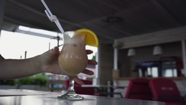 Vrouwelijke hand neemt glas met drinkstro en cocktail met sinaasappelfruit — Stockvideo