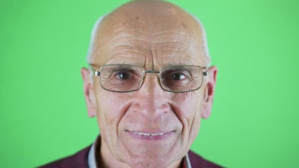 Hoofd studio shot van senior man gerimpeld gezicht met een bril — Stockvideo