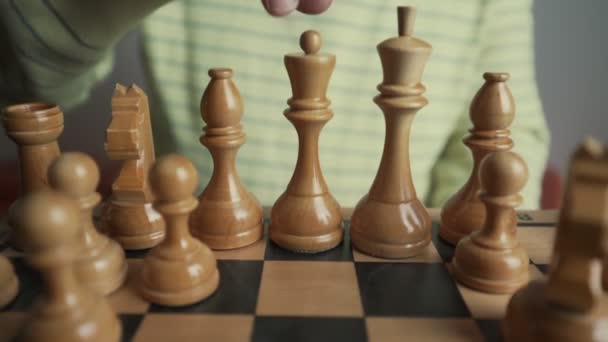 Oude man met gerimpelde handen zet koningin stuk op houten schaakbord — Stockvideo