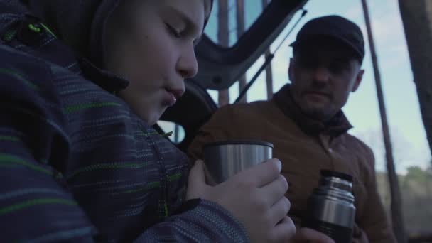 Pappa och tonårssonen sitter på bakluckan och dricker hett te. — Stockvideo