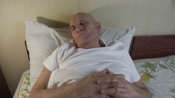 Hombre retirado acostado en la cama con los ojos cerrados y con problemas para dormir — Vídeos de Stock