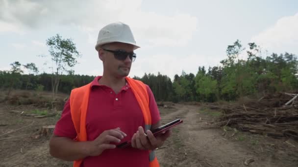 Inspecteur forestier portant un casque et un gilet orange agitant à la main — Video