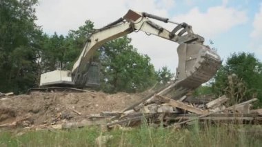 beyaz kazıcı inşaat alanında kova ile eski kütükleri taşır