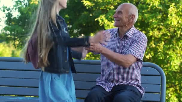 Barnbarn kommer prata med kärleksfull gammal man sitter på bänken — Stockvideo