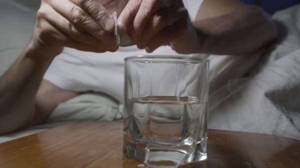 Ο ηλικιωμένος παίρνει το χάπι από την κυψέλη και πίνει νερό από το γυαλί — Αρχείο Βίντεο