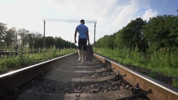 Hombre en pantalones cortos se va por ferrocarril y lleva bolsa de carretera — Vídeos de Stock