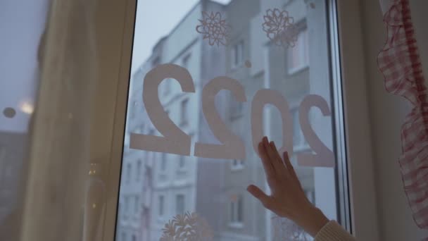 窓ガラスに紙のサインを接着する子供2022年家に立つ — ストック動画