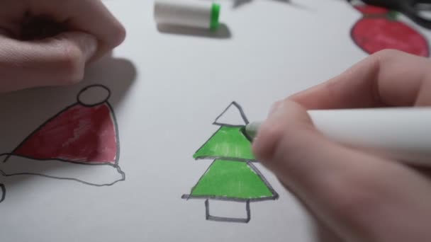 Mano del niño sosteniendo la pluma y coloreando el árbol de Navidad en color verde — Vídeos de Stock