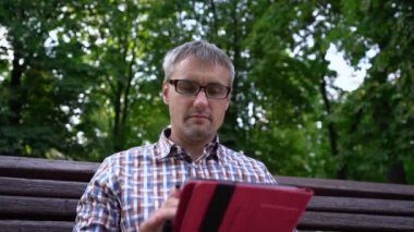 Adam sosyal ağlarda geziniyor, şehir parkında havanın tadını çıkarıyor.