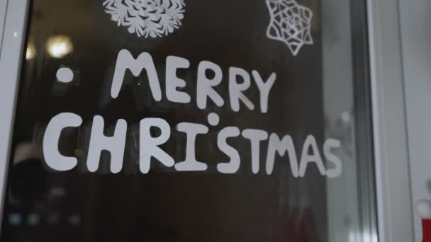 Személy behúzása függöny és elrejtése Boldog Karácsonyt felirat ablaküveg — Stock videók