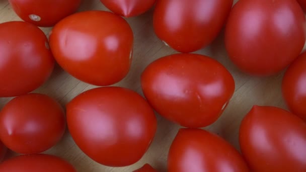 Groupe de tomates rouges mûres tournent sur fond en bois vue de dessus — Video