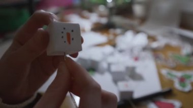 Elinde iğneyle kadın eli İpliğe kağıt kardan adam biblosu bağlıyor