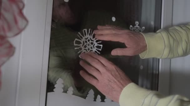 Persona masculina decorando vidrio de la ventana del hogar con copo de nieve de papel. — Vídeos de Stock