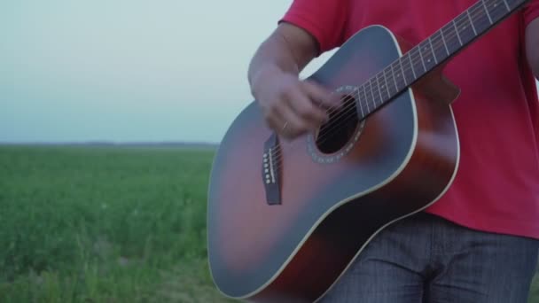 Estrecha vista de la mano del hombre que toca la guitarra acústica de pie al aire libre — Vídeo de stock