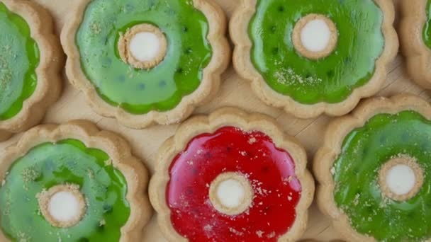 Baked biscuit cakes with colorful jam inside rotate on wooden background — Vídeo de Stock