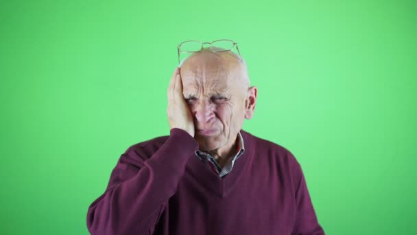 Frustrated elder man making face while standing against green background — Stock Video