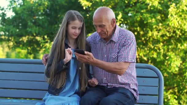Glad flicka och farfar surfa internet med mobiltelefon — Stockvideo