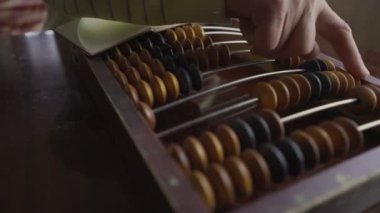 Eski ahşap abaküs ve not defterine veri yazan olgun bir adam.