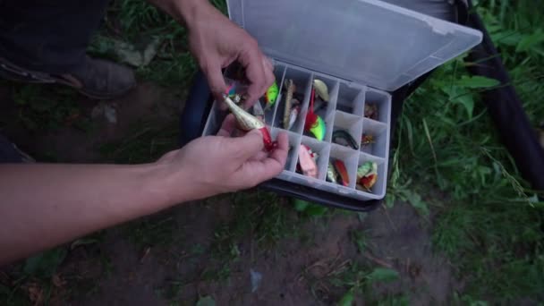 Рибалка по черзі виймає приманки з риболовецької коробки і вибирає для використання — стокове відео