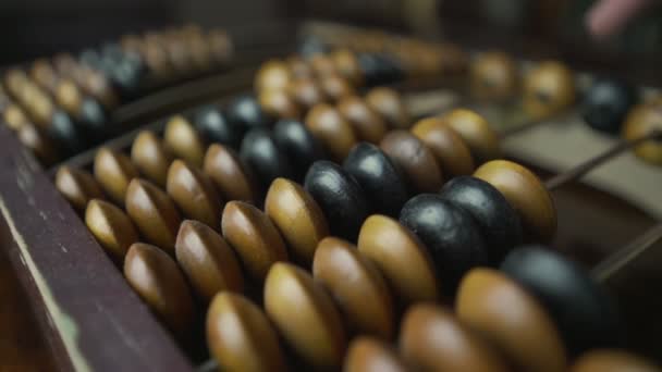 Mature man calculating with finger on wooden vintage abacus.