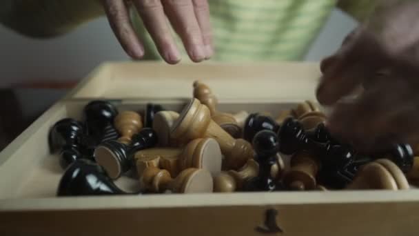 Les mains d'un joueur d'échecs mature mettent des pièces d'échecs dans une boîte en bois — Video