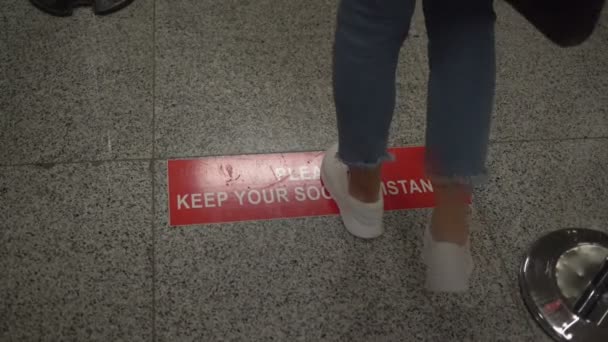 Person standing on line with inscription Please keep your social distance — Stock Video