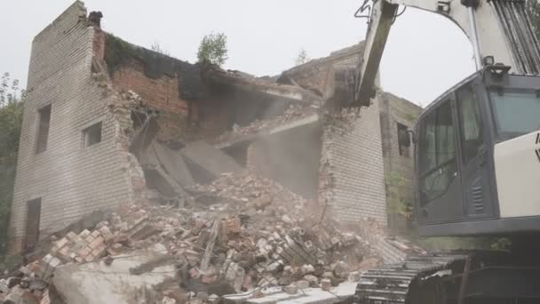 Экскаватор работает и сносит древнюю кирпичную стену на разрушенном месте — стоковое видео