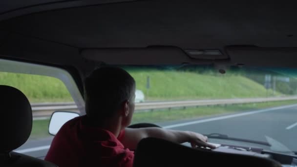 Hombre con el pelo corto en camisa roja mientras conduce el coche hablando por teléfono — Vídeo de stock