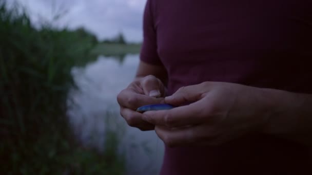 Pescador de pé na costa do lago atribui oscilador para fechar de perto — Vídeo de Stock