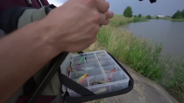 Homem coloca isca de caixa de pesca pendurado sobre seu ombro segurando vara de pesca — Vídeo de Stock