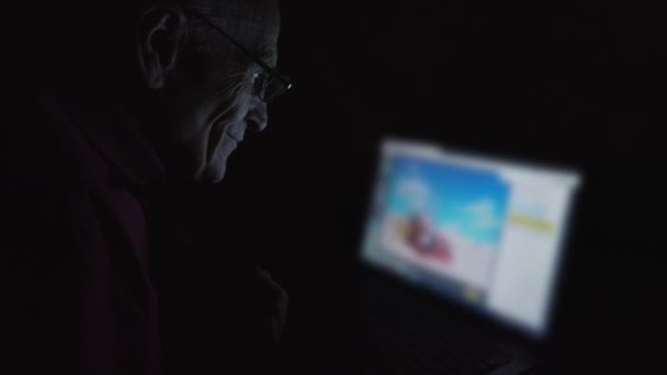 Senior pria duduk di meja di rumah dan menonton gambar musim panas — Stok Video