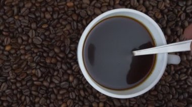 Kişi el, kahve çekirdekleri ile kaşığı karıştırır.
