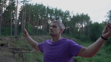 Gözleri kapalı bir adam uçurumun kenarında duruyor ve meditasyon yapıyor.