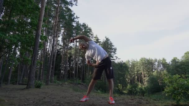 Man in sports uniform makes exercisein on nature — Stockvideo