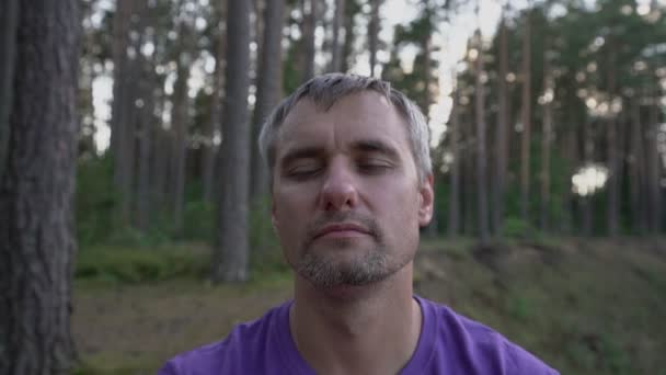 Gray haired man on nature meditates with closed eyes — Stock video