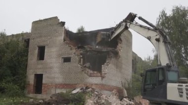 Buldozer inşaat alanında çalışıyor ve eski tuğla duvarı yıkıyor.