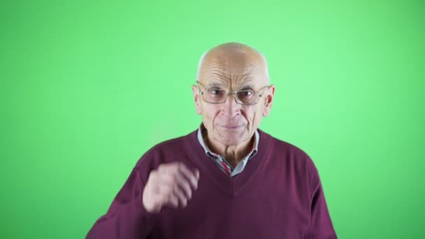 Elderly teacher looking from under glasses isolated on green background — Stockvideo