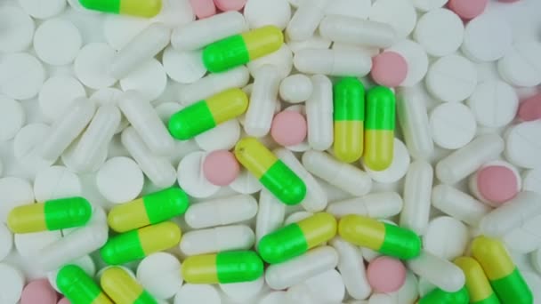 Different white and colorful medicine pills rotate in pile. — Wideo stockowe