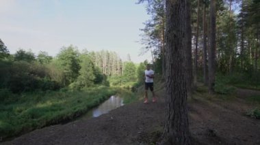 Spor giyimli bir adam nehir kenarındaki uçurumun kenarında koşuyor.