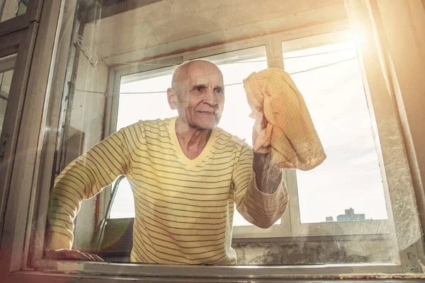 Pessoa mais velha do sexo masculino limpeza sujo janela de vidro na varanda — Fotografia de Stock