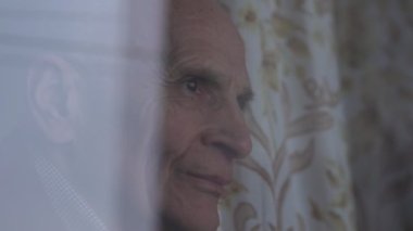 Gülümseyen yaşlı adam pencereden bakıyor ve ailesini bekliyor.