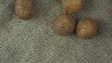 Çuval bezi arka planına düşmüş çiğ patates ampulleri.