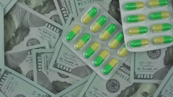 Cápsula médica verde y amarilla en ampollas rotan sobre nosotros dólares fondo — Vídeos de Stock