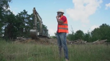 Ustabaşı telefonda inşaat alanında çalışan kazıcıya karşı konuşuyor