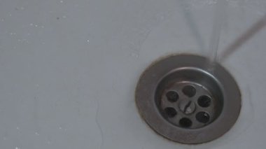 Soğuk ya da sıcak su paslı metal ızgaralı eski lavaboya akar.